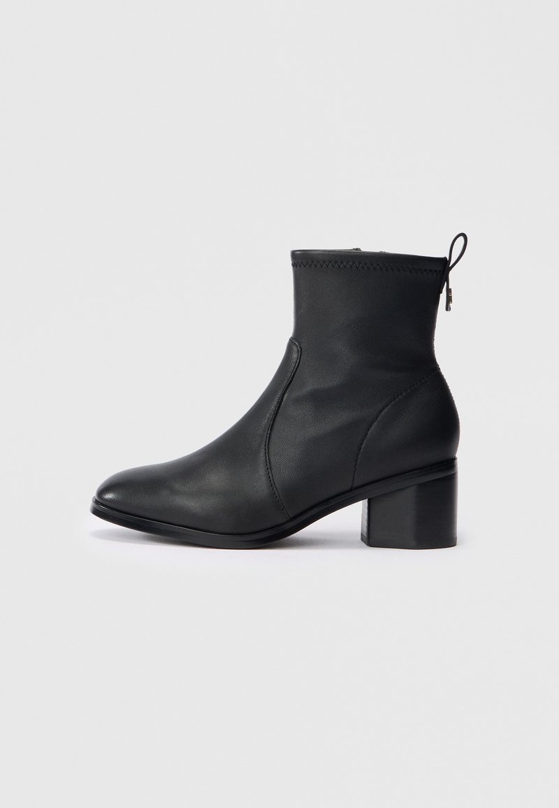 Botine negre din piele, cu un design elegant, vârf rotunjit, cusături texturate în partea de sus și toc pătrat. Include o închidere cu fermoar și un tabul de prindere.