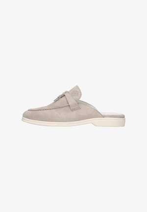 Zapatos de ante gris tipo slip-on con punta redondeada, textura suave, que presentan una correa lateral y un sutil detalle de marca en la parte superior. Suela ligera.