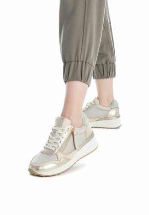 Zapatillas deportivas de malla y materiales metálicos en dorado y beige, con cremallera lateral, puntera redonda y suela blanca gruesa.