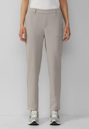 Hellgraue maßgeschneiderte Hose mit Seitentaschen und geradem Schnitt. Glatter Stoff mit feiner Textur, kombiniert mit silbernen Sportschuhen.