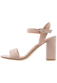 Damskie sandały na obcasie z blokowym obcasem, wykonane z jasnoróżowego zamszu, z szerokim paskiem na przodzie oraz regulowanym paskiem na kostkę z metalową klamrą.