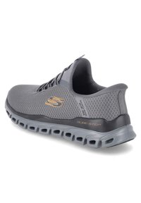 Grauer Sportschuh mit Mesh-Obermaterial, Schnürverschluss und gepolsterter Sohle. Verfügt über Glide-Step-Logo an der Ferse und strukturierte Akzente.