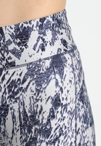 High-waisted leggings in a stretchy fabric featuring a blue and white abstract pattern. Includes flatlock seams for comfort.