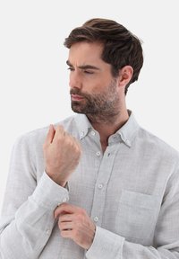 Camicia button-up grigio chiaro con una sottile trama a righe, caratterizzata da una tasca sul petto, polsini con bottoni e un design del colletto classico.