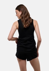 Haut sans manches noir avec un col rond, texture lisse et détails de couture subtils, associé à un short noir assorti.