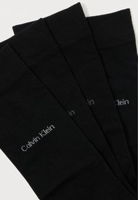 Czarne bawełniane skarpetki z teksturowanym mankietem, z subtelnym szarym logo "Calvin Klein". Trzy pary ułożone na sobie.