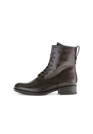 Bottines en cuir marron avec un bout arrondi, à lacets à l'avant et un petit talon. Elles sont dotées d'une sangle à l'arrière pour un enfilage facile.
