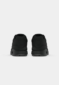 Svarte Nike Air joggesko med teksturert overdel, polstret krage og tykk såle med synlig luftdemping. Minimalistisk design med preget logo.
