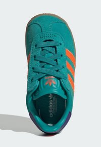 Turkos sneaker med oranga ränder, strukturerad mocka övre, vadderad tunga och gummisula; har en märkesinläggssula.