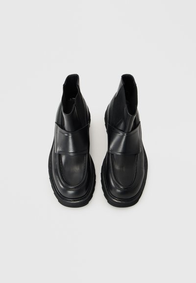 Bottes de cheville en cuir noir avec une finition lisse, un bout arrondi et des panneaux latéraux en élastique. Semelle en caoutchouc épaisse avec une texture antidérapante.