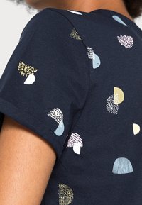 Camiseta de manga corta azul marino con una textura suave que presenta elementos de patrón abstracto multicolores en blanco, dorado, azul y rosa.
