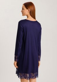 Vestito blu navy con maniche lunghe, realizzato in tessuto morbido, con dettagli in pizzo sui polsini e sull'orlo. Taglio semplice e rilassato.