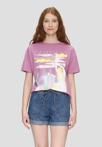 Lila Baumwoll-T-Shirt mit kurzen Ärmeln, ausgestattet mit einem bunten Grafikdesign von Meerelementen und einer Figur, kombiniert mit Jeansshorts.