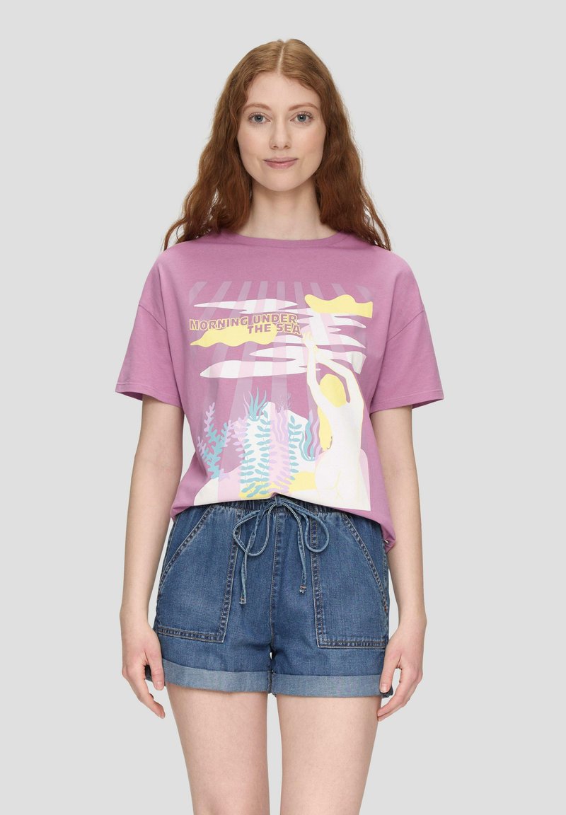 Lila Baumwoll-T-Shirt mit kurzen Ärmeln, ausgestattet mit einem bunten Grafikdesign von Meerelementen und einer Figur, kombiniert mit Jeansshorts.