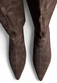Hnedé semišové čižmy s špicatou špičkou a hladkým povrchom, s priliehavým zvrškom a bezšvovým dizajnom na bokoch.