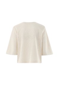 Texturierte cremefarbene Bluse mit lockerem Schnitt, weiten Ärmeln und geometrischem Muster. Der Rücken hat einen runden Ausschnitt und eine glatte Oberfläche.