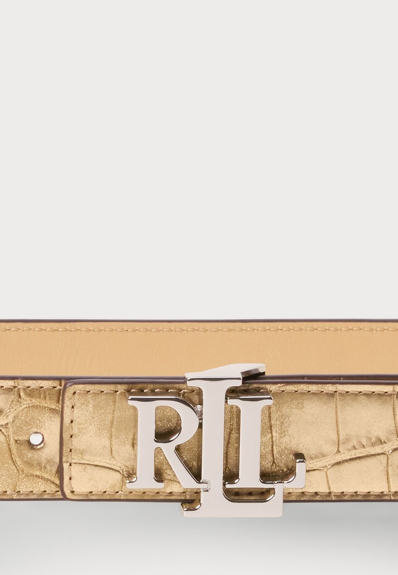 Goldfarbener Kunst-Krokodil-Leder-Gürtel mit einer silbernen Logo-Schnalle. Er zeichnet sich durch eine glatte Textur und ein kontrastierendes, hellbraunes Innenfutter aus.