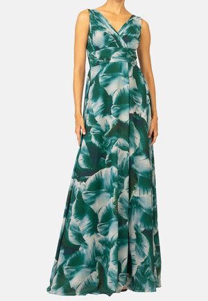 Bezrekawna zielono-biała sukienka maxi w kwiaty z dekoltem w serek i marszczonym detalem w talii, noszona przez stojącą modelkę na jednolitym tle.