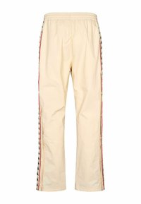 Jasnobeżowe spodnie wykonane z gładkiej tkaniny, z elastycznym pasem i bocznymi paskami ozdobionymi wzorem w czerwonym i czarnym kolorze.