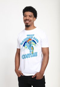 Bílý tričko s barevným grafickým potiskem poníka, text zní "Tohle je můj kostým Rainbow Dash." Tričko má kulatý výstřih.