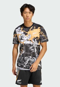 Czarna koszulka z pomarańczowymi akcentami i grafiką w stylu komiksowym. Okrągły dekolt, krótkie rękawy, wykonana z lekkiego materiału. Zawiera logo All Blacks.