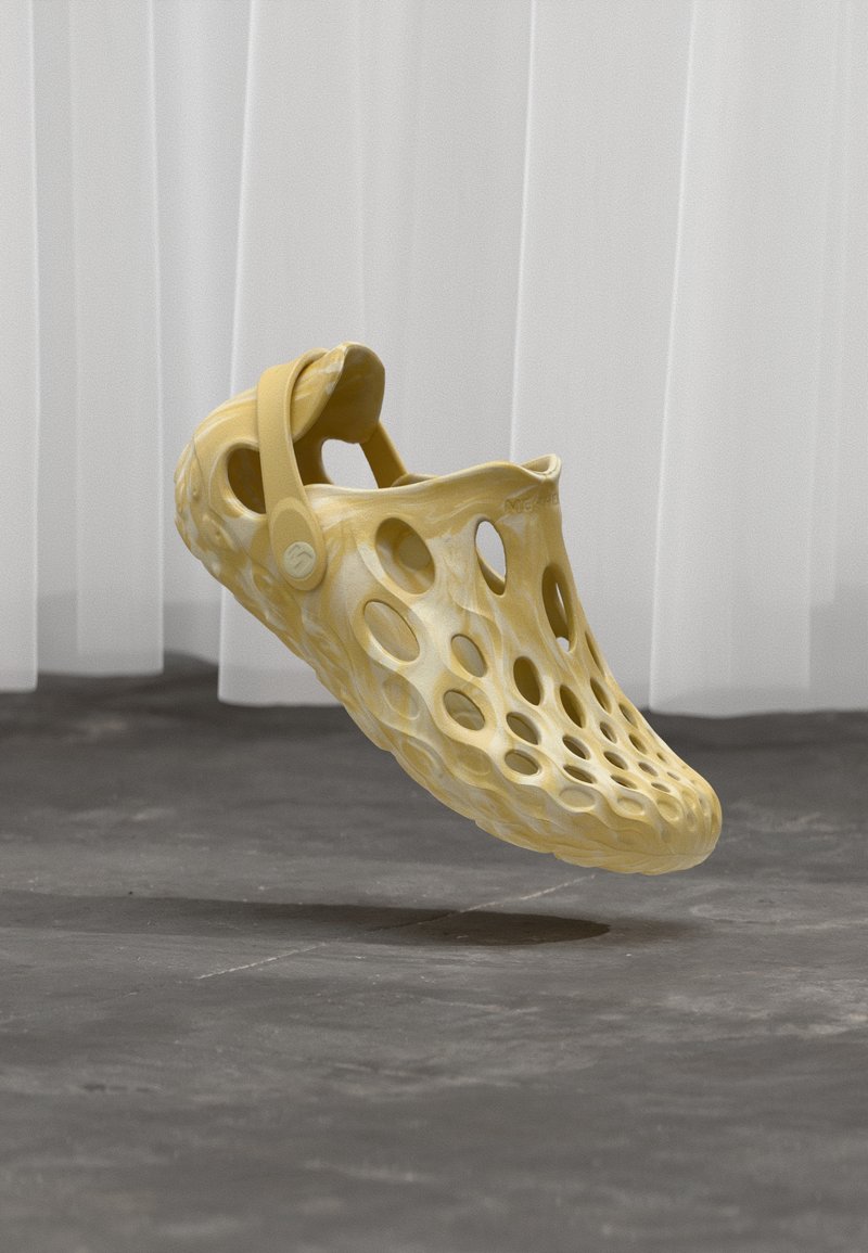 Κίτρινο ελαφρύ κλογκ με διάτρητο, υφασμένο σχέδιο και ασφαλές πίσω λουράκι. Ομαλή επιφάνεια με γυαλιστερό φινίρισμα.