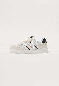 Fehér és bézs sneaker, velúr és bőr felsőrésszel, fekete csíkokkal és logórészlettel, fehér talppal és fűzőzéssel.