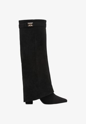 Botte noire en suède montant jusqu'au genou avec bout pointu, talon bloc et bride décorative avec boucle argentée près du haut.