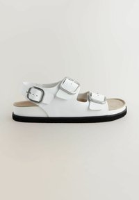 Sandali bianchi realizzati in materiale sintetico, con tre cinturini regolabili dotati di fibbie argentate, su una soletta marrone chiaro e suola nera.