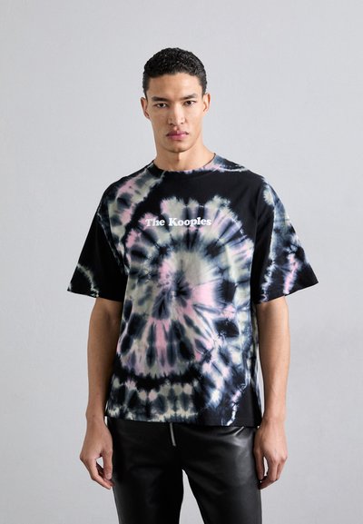 Czarny t-shirt w tie-dye z pastelowymi różowymi i niebieskimi wirami, z białym logo "The Kooples" na środku, krótki rękaw.