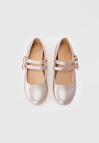 Metallische silberne Mary Jane Schuhe mit einem Design aus zwei Riemen, verziert mit herzförmigen Schnallen, und ausgestattet mit einer glatten Textur und runder Zehenpartie.
