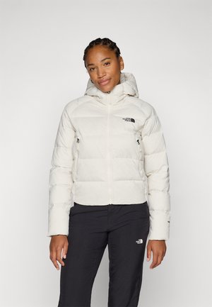 Hvit pufferjakke med hette, med glidelås og sidelommer. The North Face-logoen er vist i svart på brystet.