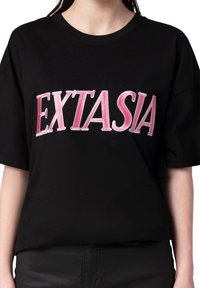 Černé bavlněné tričko s krátkými rukávy, na přední straně s velkým růžovým vyšívaným textem "EXTASIA". Jednoduchý, uvolněný střih.