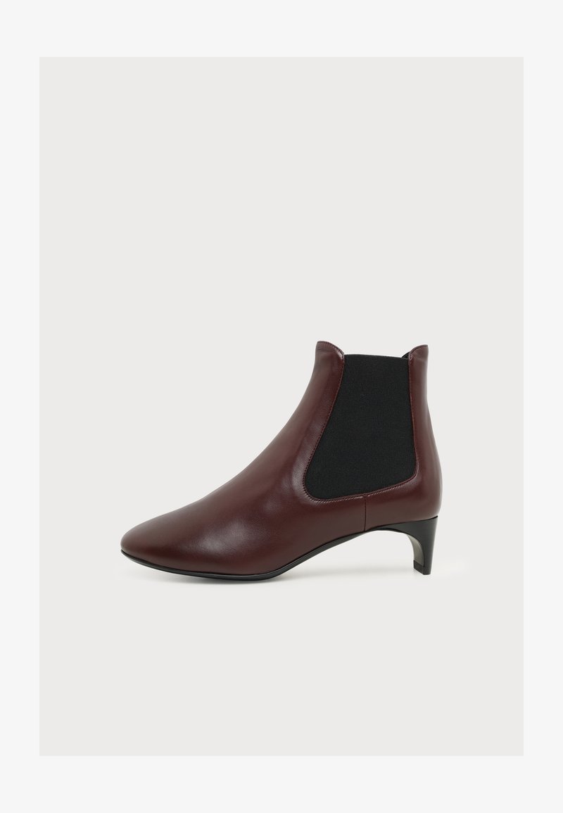 Bottine en cuir marron avec panneau latéral élastique noir et talon bas incliné sur fond blanc.