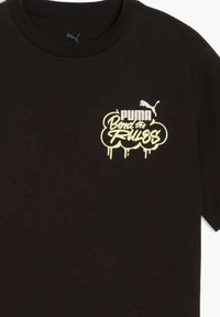 Svart bomull t-shirt med en grafik i vitt och neongult som står "PUMA Bend the Rules," med en liten logotyp ovanför texten.