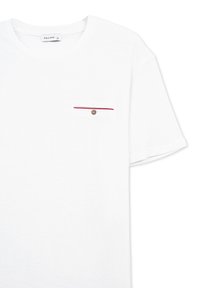 T-shirt bianco in cotone con maniche corte, caratterizzato da una piccola tasca sul petto accentuata da una striscia rossa e bianca e un dettaglio con bottoni.