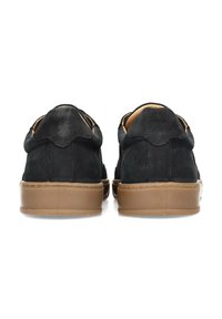 Zapatillas de ante negro con un acabado suave, punta redonda, suela de goma marrón contrastante y un discreto detalle en la parte trasera.