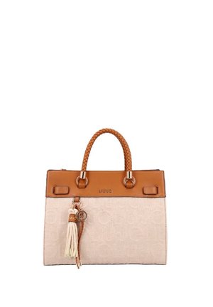 Bolso de tela beige con adorno de cuero marrón, asas trenzadas y accesorio de borla colgando de una de las asas.