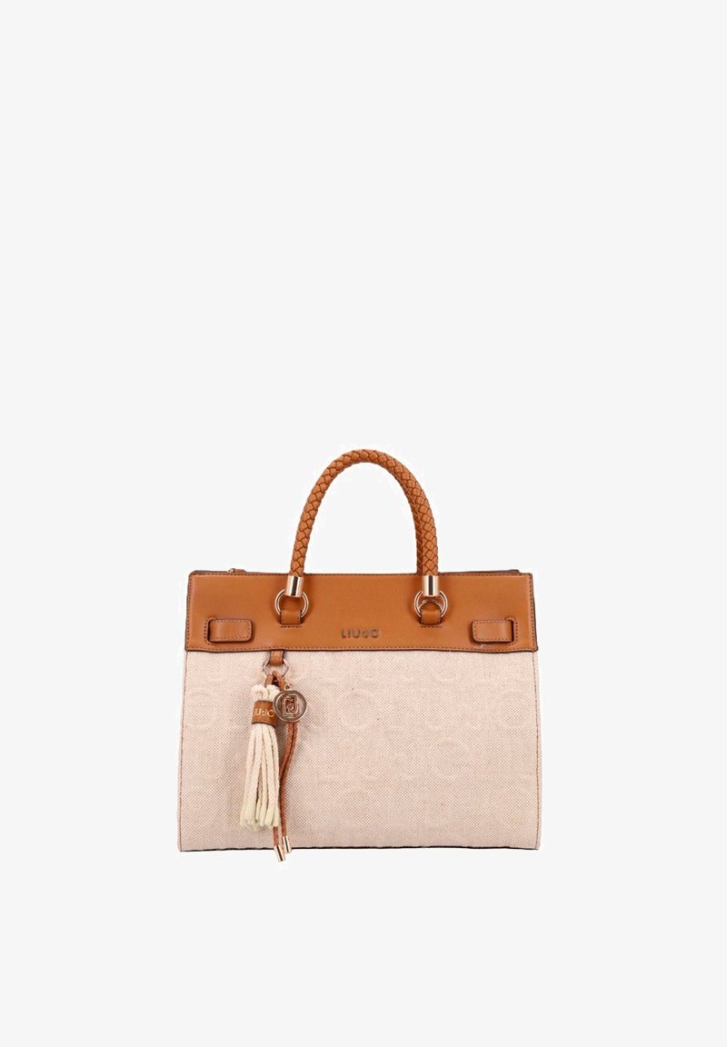 Sac à main en tissu beige avec garniture en cuir marron, poignées tressées et accessoire à pampilles suspendu à une poignée.