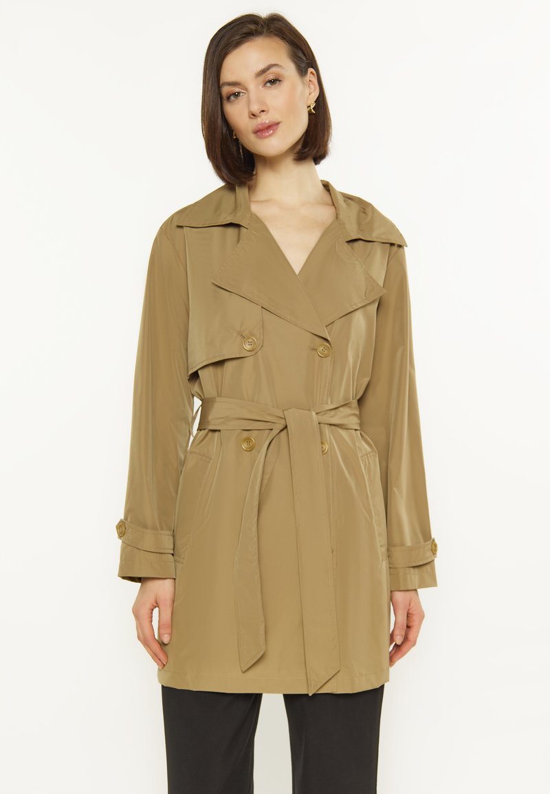 Khaki trench coat z dużym kołnierzem, na podwójne guziki i z paskiem w talii. Gładki materiał z bocznymi kieszeniami i zapinanymi rękawami.