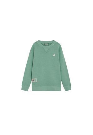 Sudadera verde de manga larga con cuello redondo, con pequeño logo blanco de calavera en el pecho y parche rectangular cerca del dobladillo en el lado izquierdo.