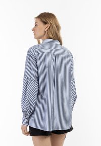 Stripet button-up skjorte i blå og hvid, har en afslappet pasform, lange ærmer og en rygdetalje. Letvægts bomuldsstruktur.