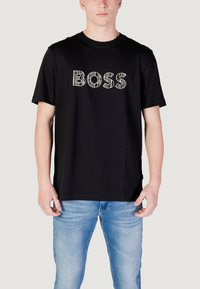 Zwarte katoenen t-shirt met een opvallende "BOSS" graphic in het wit met een textuurpatroon. Korte mouwen en een relaxed fit.