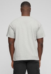 Camiseta de algodón gris con mangas cortas y cuello redondo, que presenta un corte holgado. La tela tiene una textura suave y bordes acabados.