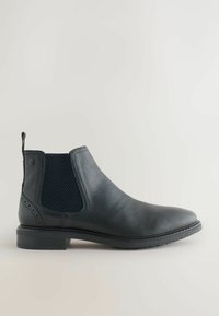 Botín Chelsea de cuero negro con panel lateral elástico, lengüeta en el talón, tacón bajo apilado y detalles de costura en la suela.