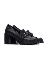 Mocasines de cuero negro con tacón cuadrado, presentan una amplia correa y herrajes metálicos. La suela cuenta con un dibujo robusto para mayor agarre.