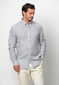 Camicia a righe in azzurro chiaro e bianco, con colletto, maniche lunghe e una vestibilità rilassata. Il tessuto presenta una trama testurizzata.