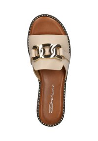 Beige schuif sandaal met een brede band, voorzien van een gouden kettingaccent. Glad, glanzend materiaal en een gevoerd tan voetbed. Zwarte rand met studs.