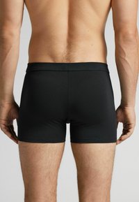 Svarta boxershorts i ett mjukt, stretchigt material; åtsittande design med resårmidja, som visar en ren, enkel silhuett.