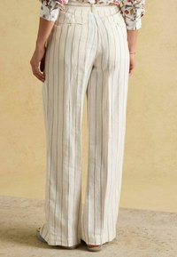 Pantaloni cu croială largă din țesătură de in respirabilă, cu dungi verticale în crem și maro deschis, prevăzuți cu două buzunare în spate și o croială lejeră.